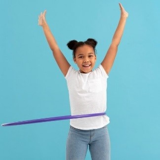 A child with her arms up and a hula hoop